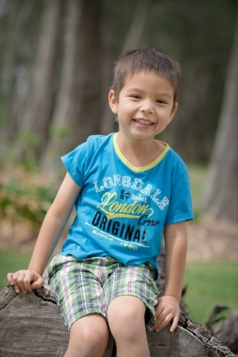 Cute mixed race boy playing in a park outside among the trees - Australian Stock Image