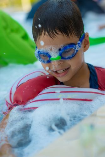 Cute mixed race boy plays in the bubbles of a backyard spa - Australian Stock Image