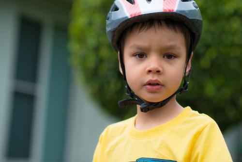 Cute mixed race boy wearing a helmet and riding his bike - Australian Stock Image