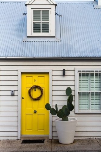 Cute white weatherboard cottage with yellow door and cactus in paddington, sydney - Australian Stock Image