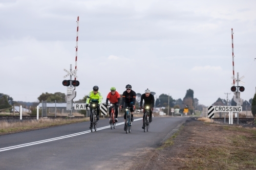 Cyclist riding across a rail crossing in the early morning - Australian Stock Image