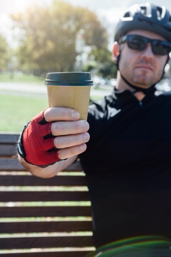 Cyclist taking a break holding a cup of coffee - Australian Stock Image