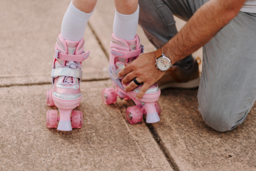 Dad helping daughter get into her roller blades. - Australian Stock Image