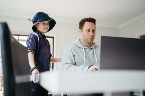 Dad helping kids with their homework using laptop. - Australian Stock Image