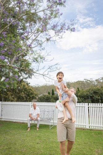 Dad holding up son holding butterfly net - Australian Stock Image