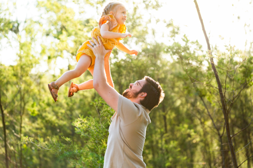 Dad playing with young daughter outside in green bushland - Australian Stock Image