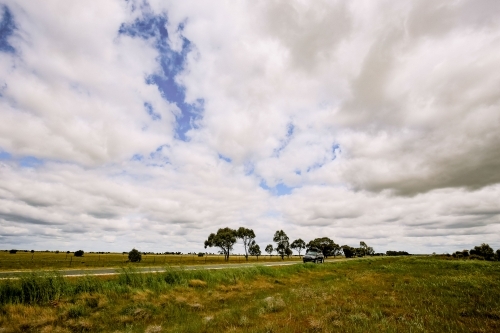 Dark grey 4x4 vehicle parked on side of country road with roof rack loaded up on road trip - Australian Stock Image