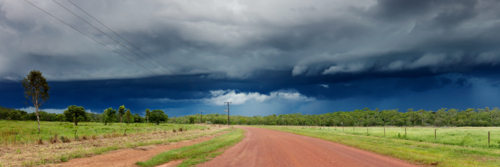 Dark storm cloud over red dirt gravel road in the Northern Territory - Australian Stock Image