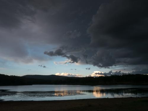 Dark storm clouds over a lake with reflections - Australian Stock Image