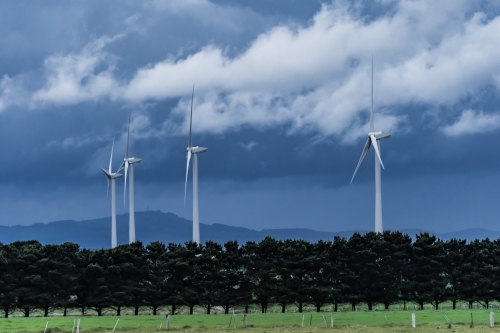 Dark stormy skies hovering over tall wind turbines - Australian Stock Image