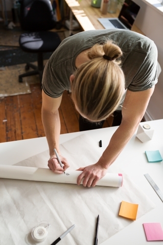 Designer addressing a tube of artwork for despatch - Australian Stock Image