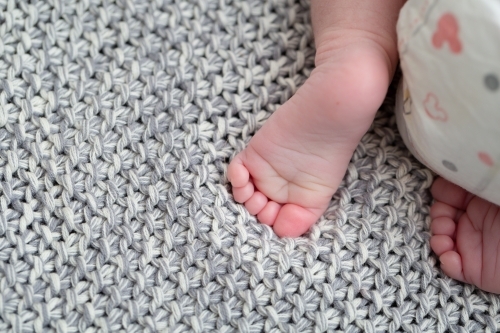 Detail of baby's feet and nappy on blanket - Australian Stock Image