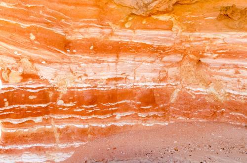 Detail shot of layered and patterned rock with orange, pink and yellow colours - Australian Stock Image