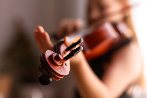 detail shot of violin scroll and pegs while a girl is practicing - Australian Stock Image