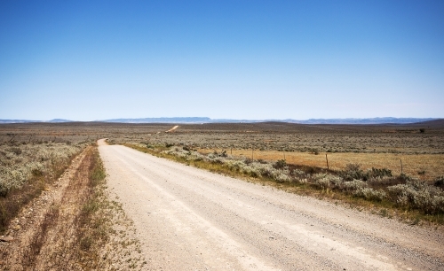 Dirt road in an arid landscape with distant hills - Australian Stock Image