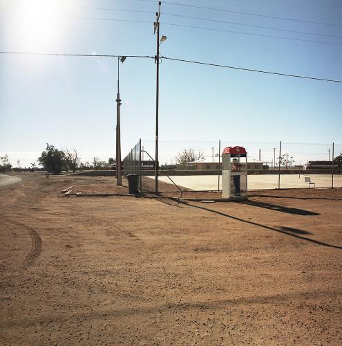 Dirt road in remote town with phone box and power lines - Australian Stock Image