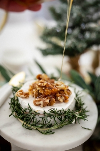 Dish of Camembert with rosemary and walnuts on decorated Christmas table - Australian Stock Image