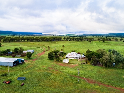 Distant homestead and other farm buildings in green home paddock - Australian Stock Image