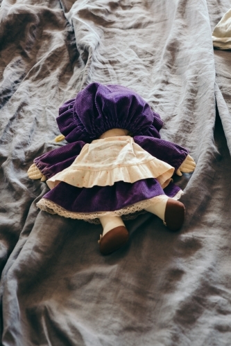 Doll face down on a bed representing drunk, tired or abandoned - Australian Stock Image
