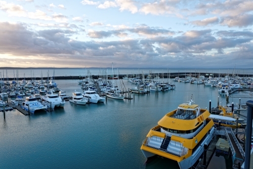 Dramatic clouds at dawn catching the light on the water Hervey Bay marina - Australian Stock Image