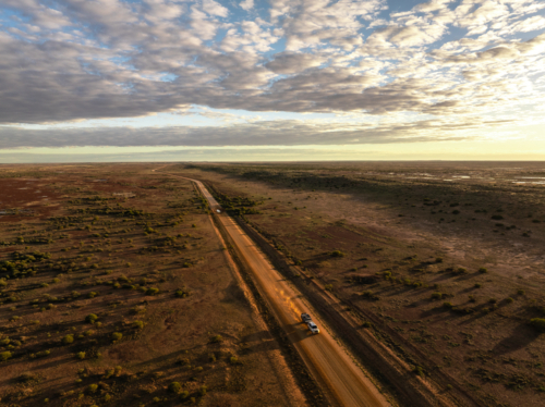 Driving along the Birdsville Track in the early morning golden hour light - Australian Stock Image