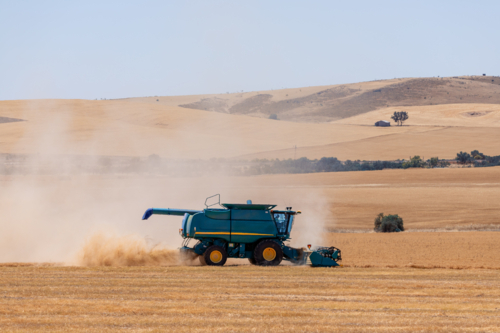 Dry-land farming machinery harvesting crop in farm paddock - Australian Stock Image