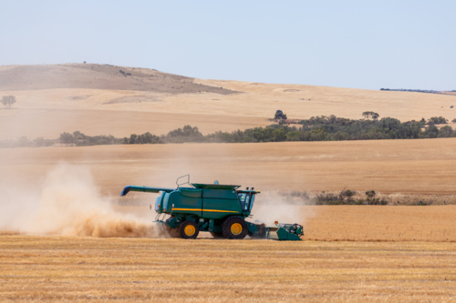 Dry-land farming machinery harvesting crop in farm paddock - Australian Stock Image