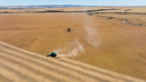 Dry-land farming machinery harvesting crop in farm paddock - Australian Stock Image