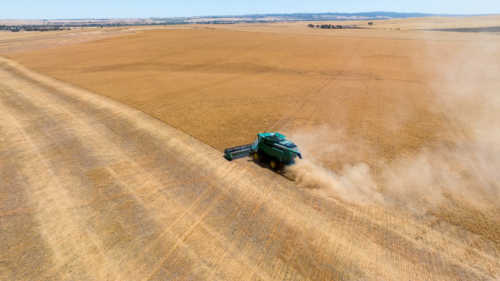 Dry-land farming machinery harvesting crop in farm paddock - Australian Stock Image