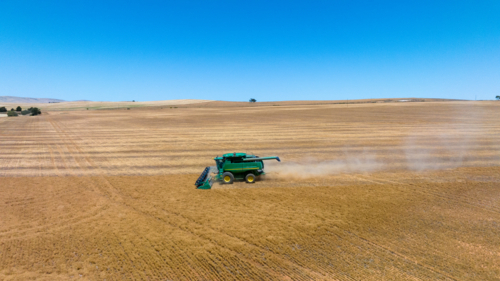 Dry-land farming machinery harvesting crop in farm paddock - Australian Stock Image