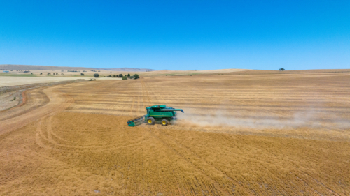 Dry-land farming machinery harvesting crop in farm paddock - Australian Stock Image