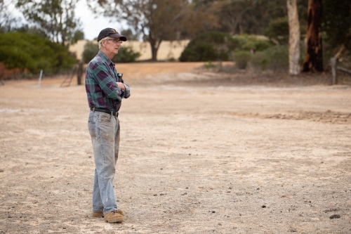 dry landscape with worker in checked shirt and jeans - Australian Stock Image