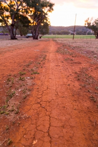 Dry red cracked earth path on a rural property at dusk