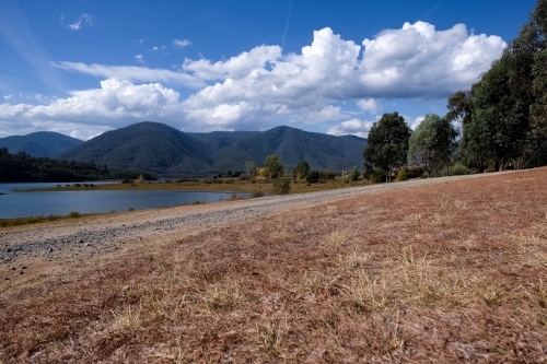 Dry valley bed with lush mountains on the background - Australian Stock Image