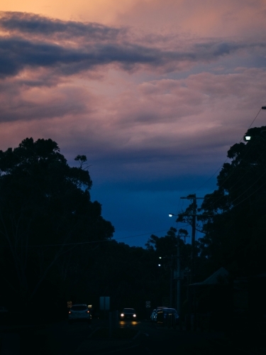 Dusk coloured clouds over dark town street - Australian Stock Image