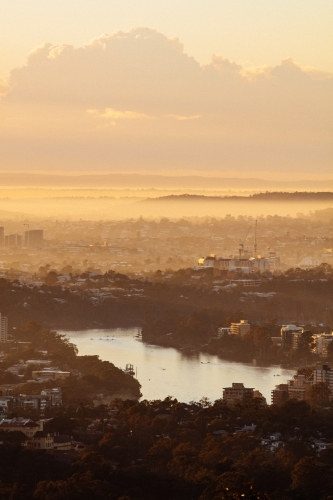Early morning golden colours with some low lying fog over the Brisbane River and suburbs. - Australian Stock Image