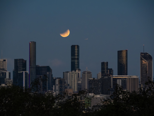Eclipse of the full moon shining over city skyline - Australian Stock Image