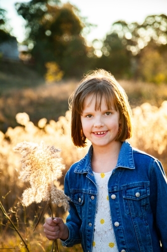 Eight year old girl outside backlit by golden sunset light - Australian Stock Image