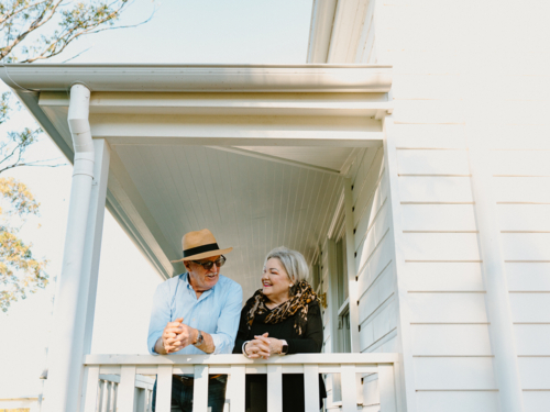 Elderly couple leaning against the wooden rails on the porch - Australian Stock Image