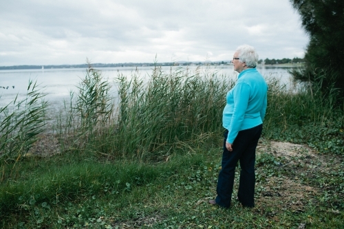 Elderly lady looking out towards a lake