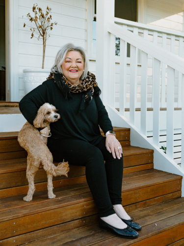 Elderly woman sitting on the wooden steps with her small dog. - Australian Stock Image