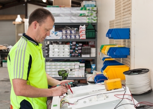 Electrician testing current with multimeter in his workshed - Australian Stock Image