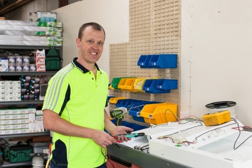 Electrician working on power board in his workshed - Australian Stock Image