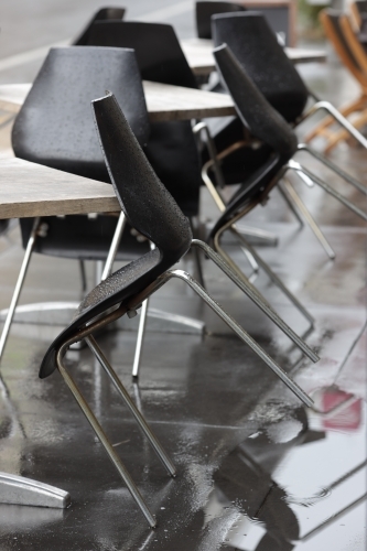 empty chairs at outdoor cafe on wet day - Australian Stock Image