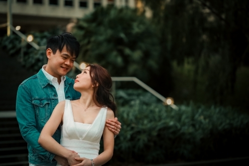Engaged couple embracing in front of steps at Melbourne's Treasury Gardens - Australian Stock Image
