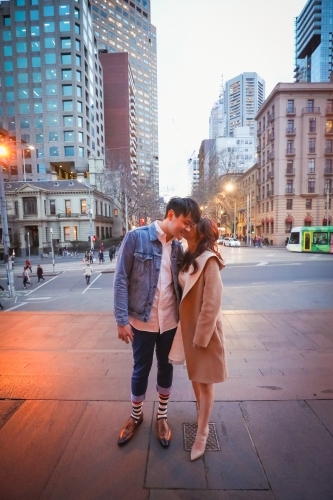 Engaged couple embracing in the city with Melbourne cityscape in background at night - Australian Stock Image