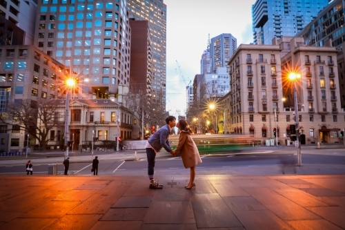 Engaged couple embracing in the city with Melbourne cityscape in background at night - Australian Stock Image