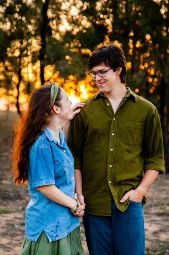 Engaged couple looking at one another backlit byt sunset light - Australian Stock Image