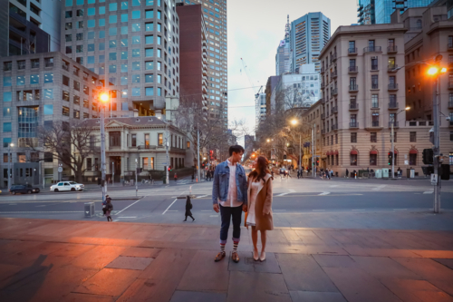 Engaged couple side by side in the city with Melbourne cityscape in background at night - Australian Stock Image