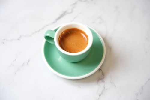 Espresso in teal cup on marble table - Australian Stock Image